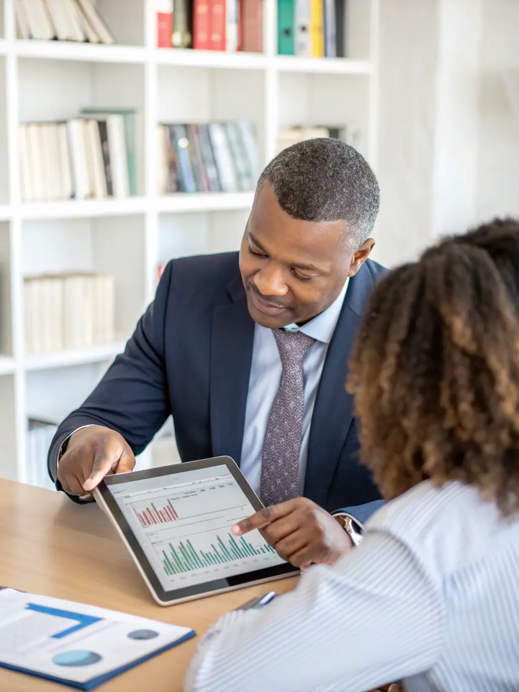A South African business owner reviewing financial reports with a coach, illustrating strategic business planning.
